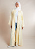 This open pleat abaya in buttercream boasts exquisite neat pleating that cascades down the placket and cuffs, offering a loose yet structured fit for all body types. Perfect as a quick cover-up for everyday outfits, or paired with one of our full slips for a more elegant ensemble. 