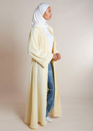 This open pleat abaya in buttercream boasts exquisite neat pleating that cascades down the placket and cuffs, offering a loose yet structured fit for all body types. Perfect as a quick cover-up for everyday outfits, or paired with one of our full slips for a more elegant ensemble.