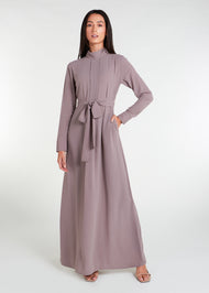 This Box Pleat Abaya Taupe features a fluid, A-line cut with a neat box pleat that runs from the high neck line to the bottom of the garment. The abaya is lightweight and airy, and a slip is necessary to wear underneath.