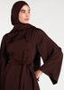 This mid-weight abaya boasts a subtle shine and features a flared silhouette, an oriental-style neckline, self fabric buttons and includes an optional belt. Dark brown colour. 