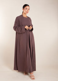 This elegant Two Piece Open Abaya set includes a Full Sleeve matching inner dress. Perfect for everyday wear, it can also be dressed up with accessories for an evening look. The open abaya can be worn as a maxi on its own or paired with the inner dress for a stylish ensemble. In brown.