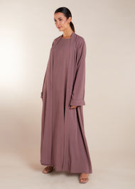 This elegant Two Piece Open Abaya set includes a Full Sleeve matching inner dress. Perfect for everyday wear, it can also be dressed up with accessories for an evening look. The open abaya can be worn as a maxi on its own or paired with the inner dress for a stylish ensemble. In purple.