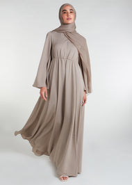 This waist pleat abaya in beige boasts a flattering fit with light pleating on the waist and bodice. Perfect for summer, the flared bell sleeves add a breezy touch, while the discreet button opening on the front of the bodice adds a thoughtful detail.