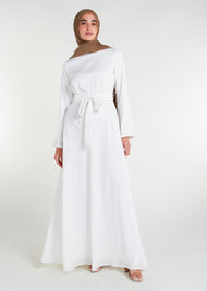 This fully lined white abaya boasts subtle pleats strategically placed at the waist to gently accentuate your figure. An optional belt is included for those who prefer a cinched waist. 